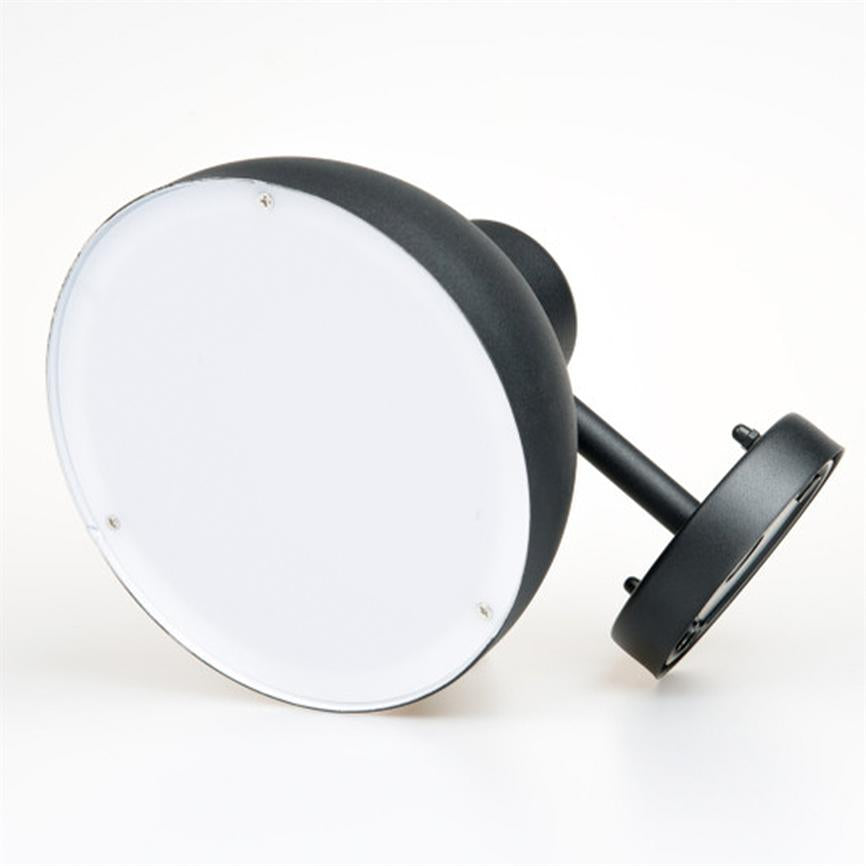 Sort rund væglampe med hvidt, fladt diffusorcover ligger på siden på en hvid baggrund; metalarm og monteringsplade synlige, enkel moderne udformning og tre små skruer i fronten.