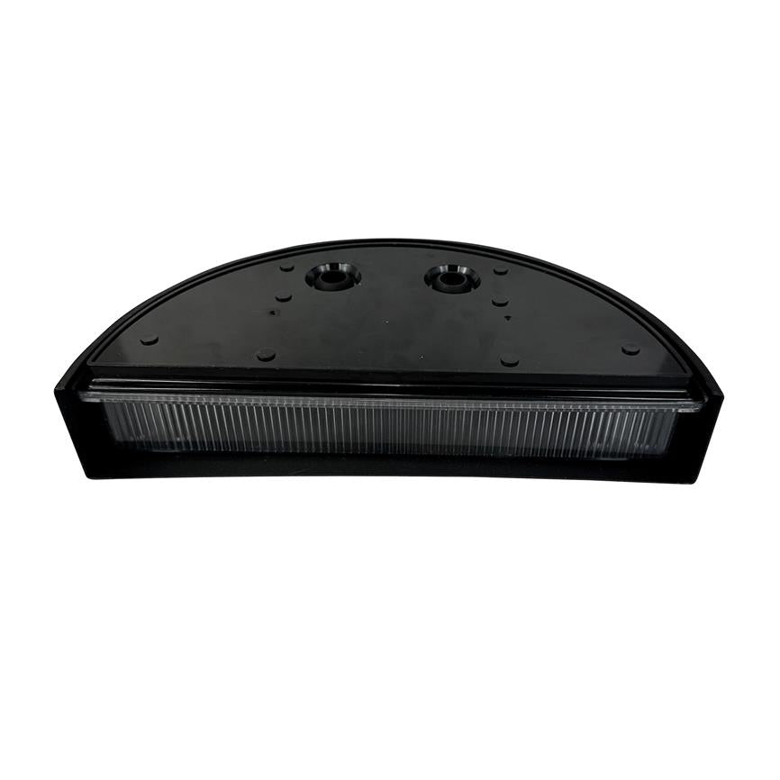 Halvcirkelformet sort plastenhed (lygtehus) med klar, ribbet frontlinse; to montagesænkede huller øverst; flad underside; placeret isoleret mod en hvid baggrund.