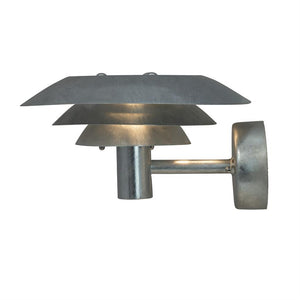 Væglampe i børstet metal, tre lagede skærme afgiver varmt, dæmpet lys; cylindrisk arm forbinder lampe til rund vægbeslag, placeret mod en neutral hvid baggrund.