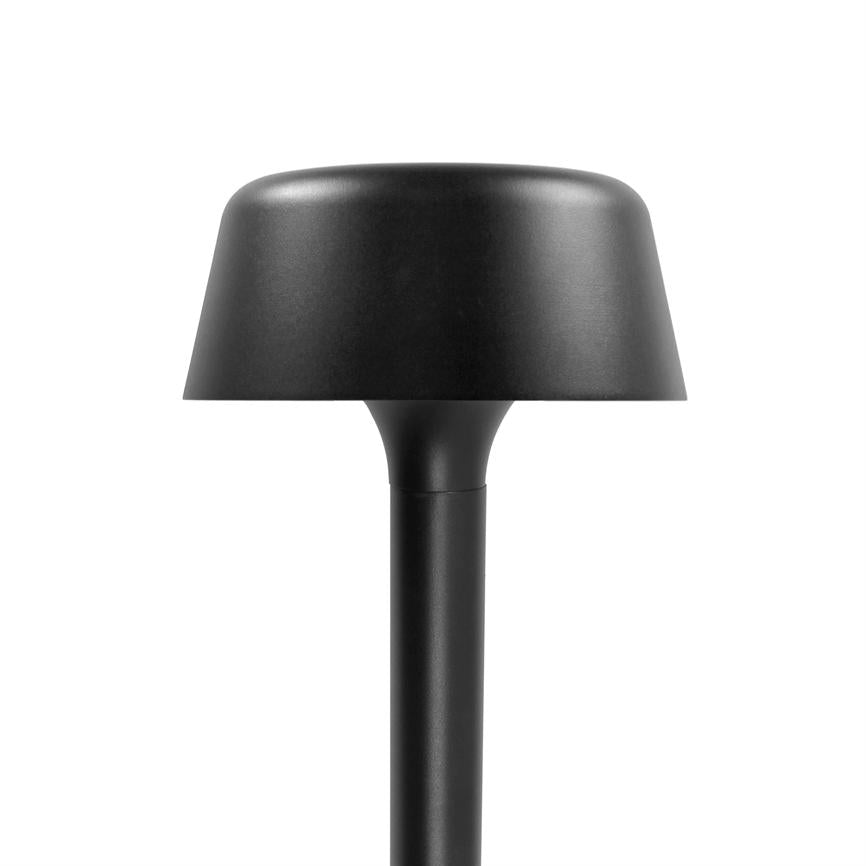 Sort bordlampe med rund, svampeformet skærm, står oprejst på en slank stang; mat sort overflade, minimalistisk design, placeret mod en ensartet hvid baggrund i et fotostudie.