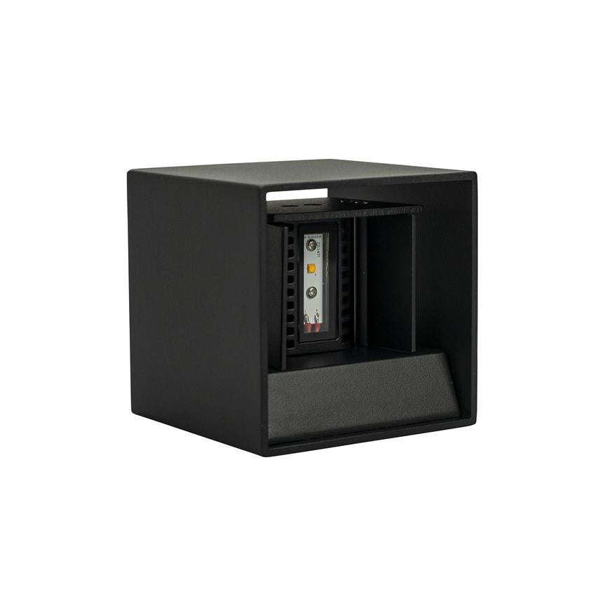 Sort kubisk armatur viser et indvendigt LED‑modul; modulet sidder bag et åbent frontfelt, rettet fremad/nedad, med mat finish og rumligt indhak, vist på hvid baggrund.