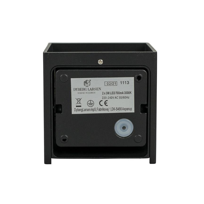 Et firkantet sort LED-armatur viser sin bagside; etiket, skruer og en rund gummikabelgennemføring er synlige mod en ensartet hvid baggrund.
 
 Tekst på etiketten:
 DYBERG LARSEN
 DESIGNED IN DENMARK
 02/21 1113
 2 x 3W LED 700mA 3000K
 220-240V AC 50/60Hz
 DybergLarsen ApS,Fabriksvej 1,DK-5466 Asperup