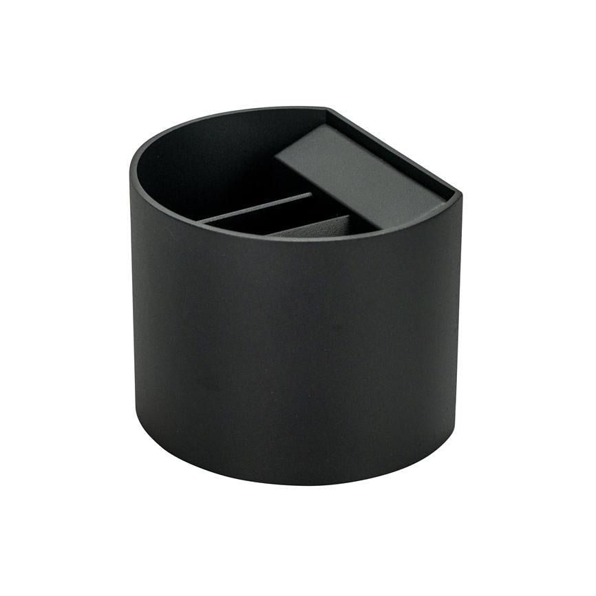 En sort cylindrisk penneholder viser indvendige rum og en vippet opdelingsplade; den står alene på en hvid baggrund.