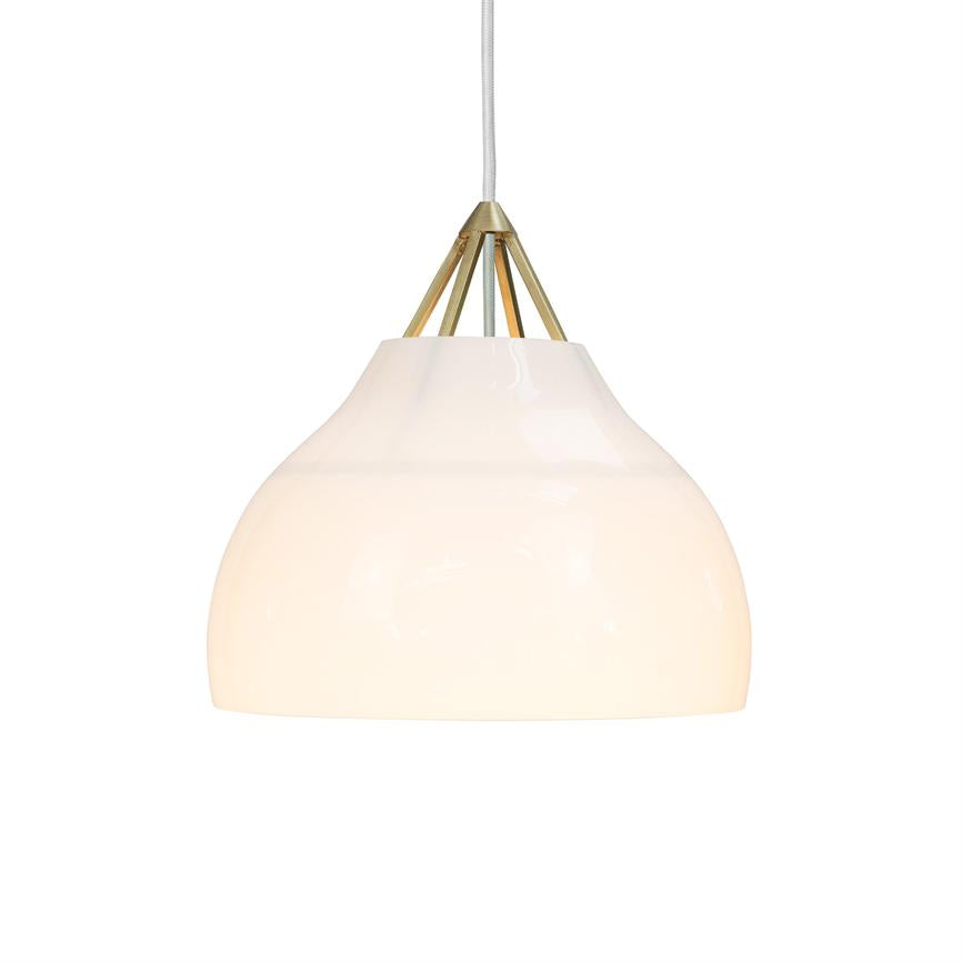 Hvid glaspendel hænger og udsender blødt, varmt lys foran en neutral hvid baggrund; messingbeslag øverst forbinder den til en hvid ledning.