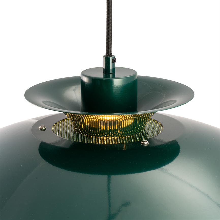 En mørkegrøn, blank metal hængelampe udstråler varmt, gult lys gennem en perforeret guldfarvet ring, hængende i en sort stofledning mod en neutral, hvid baggrund.