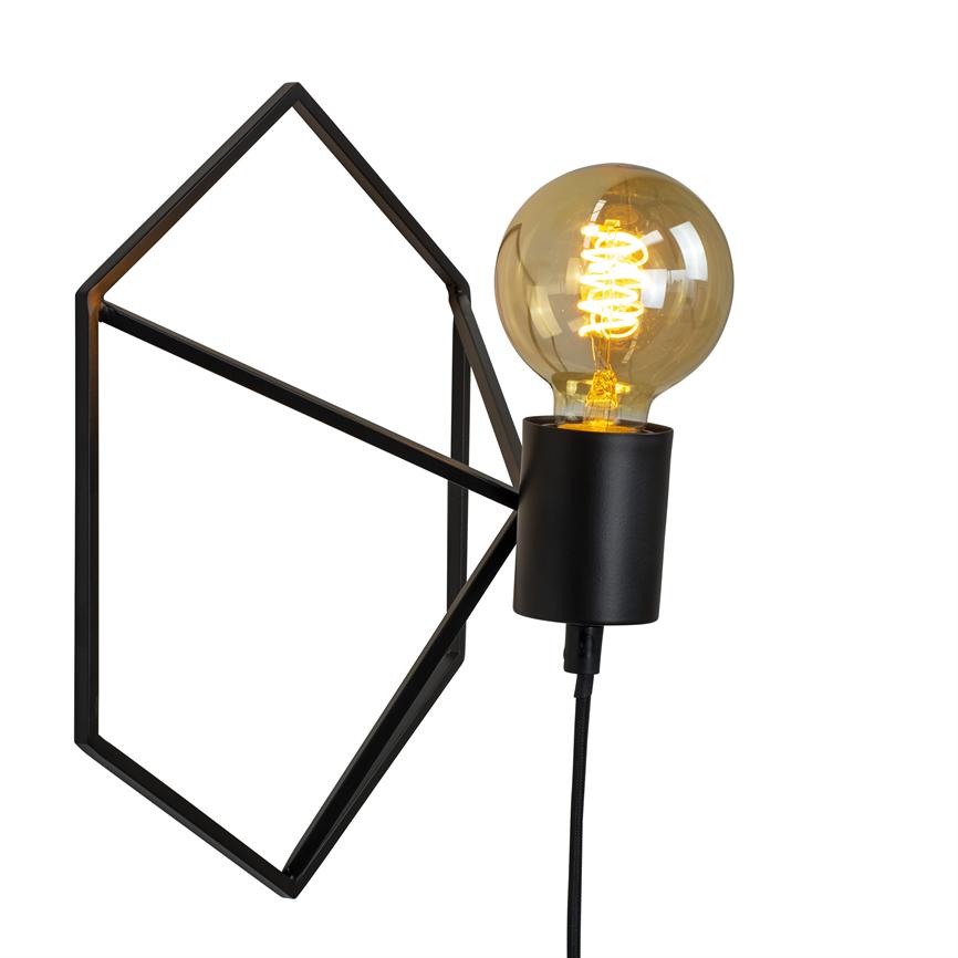 En væglampe lyser med en synlig, varmglødende pære; pæren sidder i en sort fatning og hænger fra en sort stofledning, monteret på en åben geometrisk sort metalramme mod hvid baggrund.