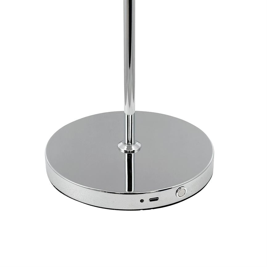 Rund, spejlblank krom lampefod står på hvid baggrund; den har en lodret stang, en rund tændknap, et lille hul (LED) og en USB-port langs kanten.