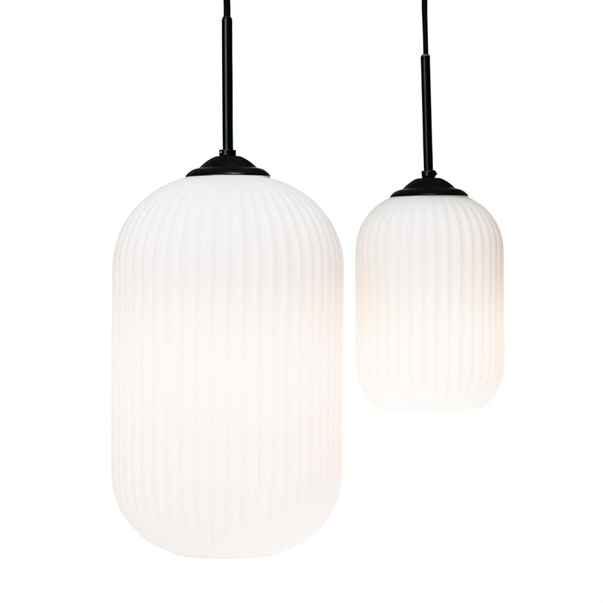 To hvide, rillede pendellamper hænger i sorte ledninger foran en neutral hvid baggrund, det ene større og det andet mindre, med blødt, jævnt lys.
