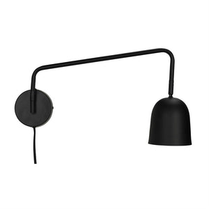 Sort væglampe med rundt vægbeslag, lang udstrakt arm, der holder en klokkeformet skærm; en ledning hænger ned mod en neutral hvid baggrund.