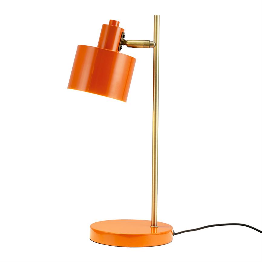 En orange skrivebordslampe vipper med cylindrisk skærm nedad; tynd messingstang forbinder skærm og rund base, sort ledning ligger ved basen på en neutral hvid baggrund.
