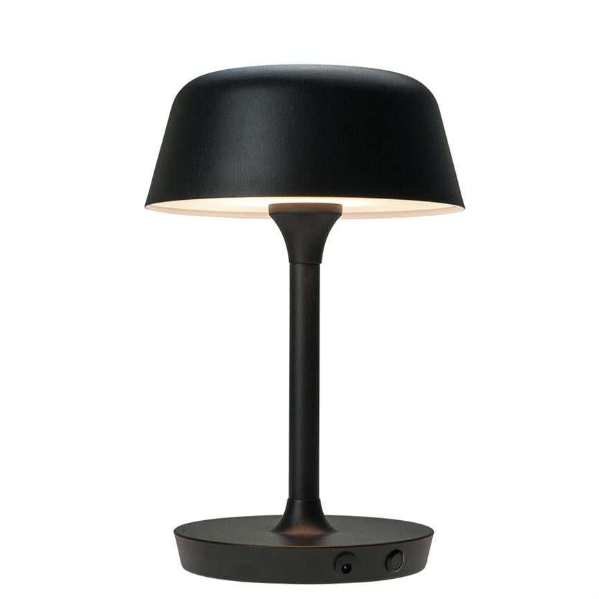 Bordlampe med rund, sort skærm på slankt skaft: udstråler blødt, nedadrettet lys over en rund fod, placeret mod en ren, hvid baggrund.