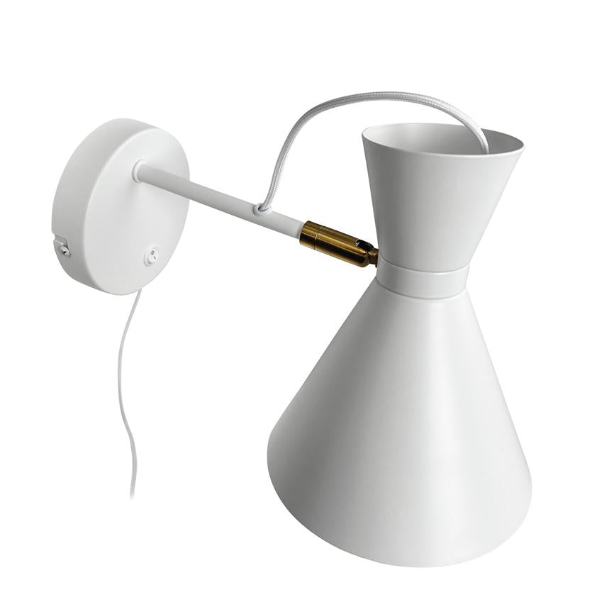 Væglampe hænger skråt fra en hvid arm, forbundet med en tekstileret ledning og en lille guldfarvet kobling; stor hvid kegleskærm peger nedad, monteret på rund vægplade mod hvid baggrund.