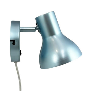 Metalvæglampe peger nedad; skærm er hængslet til en rund vægbase med synlig ledning, mat lyseblå metalfinish mod hvid baggrund.