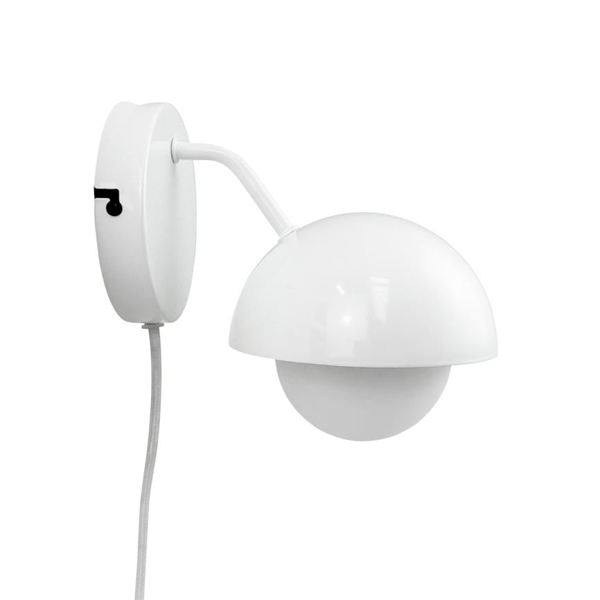 Hvid væglampe hænger med en halvkugleformet skærm, der dækker en kugleformet pære; arm buer fra en oval vægplade, og en stofbeklædt ledning hænger ned mod venstre.