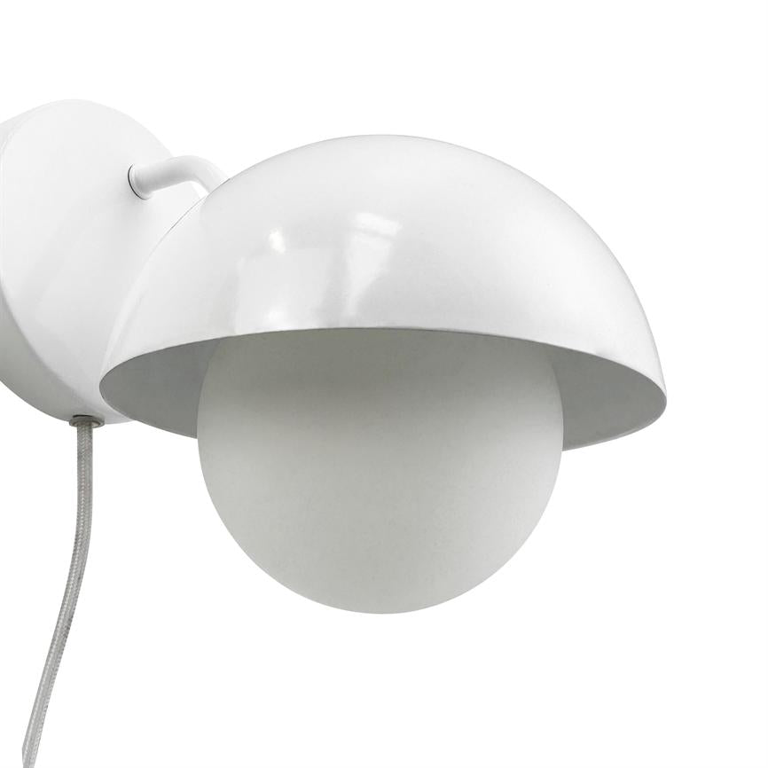 En hvid væglampe hænger og skærmer en rund opalglaspære med en halvkugleformet metallskærm; monteret på et vægbeslag med synlig tekstilledning mod hvid baggrund.