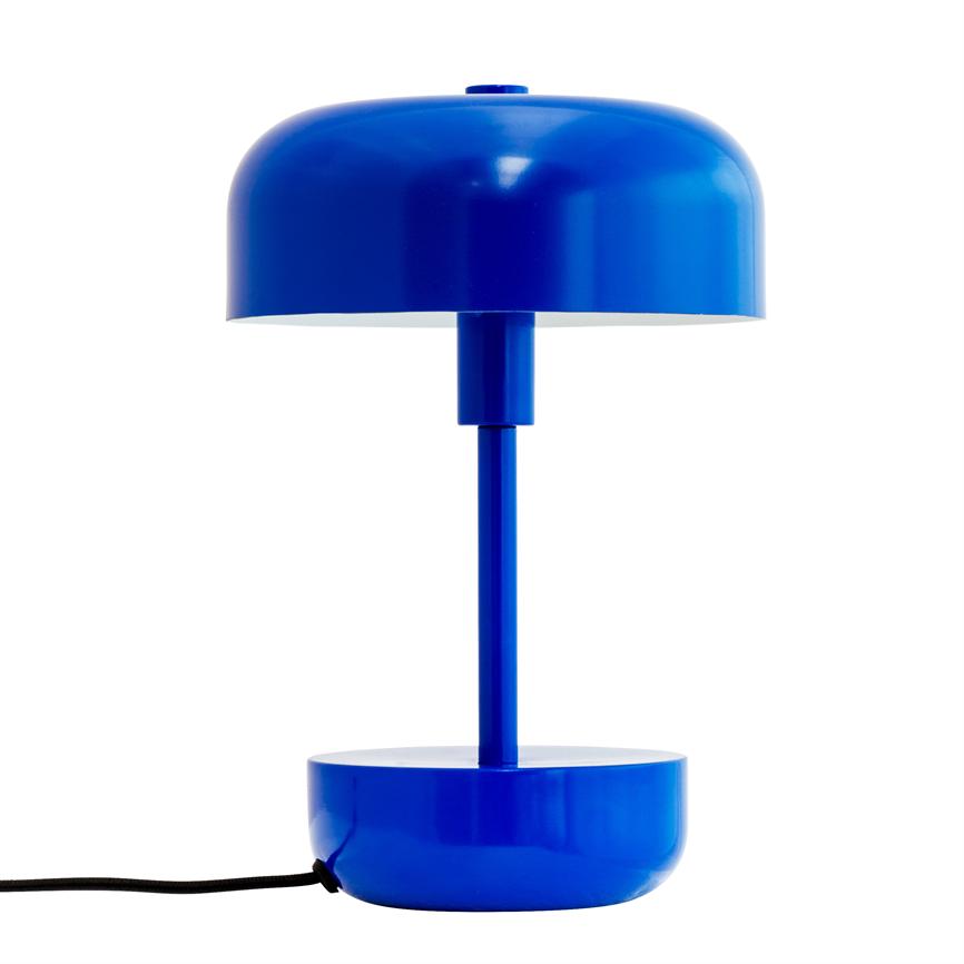 En blå metal bordlampe med rund skærm og cylindrisk fod står midt på en hvid baggrund; en sort ledning stikker ud fra lampens base.