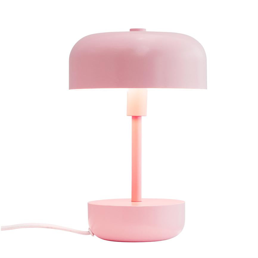 Rosa bordlampe lyser blødt; en slank stang forbinder en kuppelformet skærm med en rund fod, placeret på en ensartet hvid baggrund.