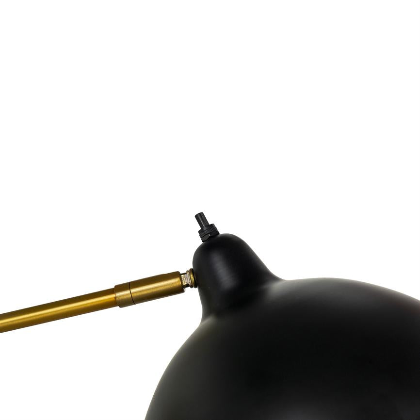 Sort, buet lampehoved forbundet til en gylden metalarm gennem et justerbart led, vinklet mod højre på en ensartet hvid baggrund.