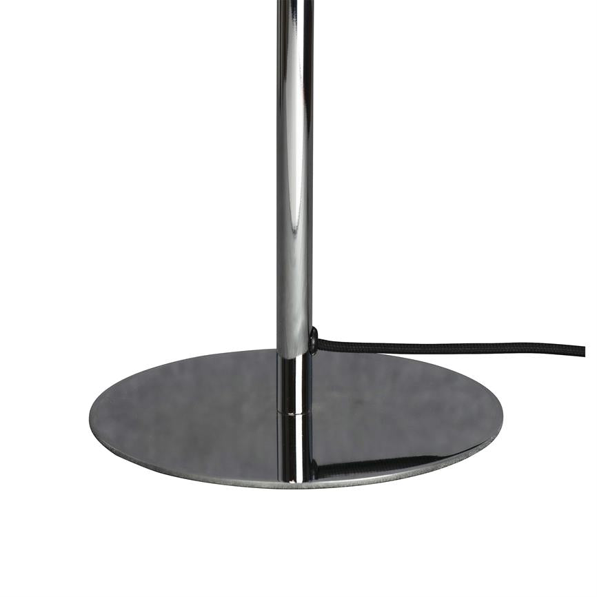 Krom metalstang står lodret på en lav, rund fod; et sort, stofbeklædt kabel løber ud fra stangen; enkel hvid baggrund.