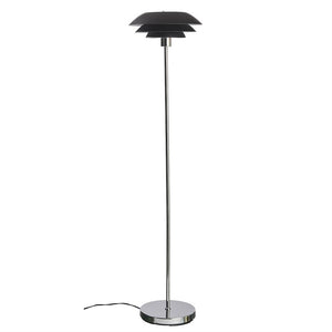 Gulvlampe står oprejst med en slank kromstang og rund kromfod; tre-lags sort lampskærm øverst, sort led ligger løst på hvid baggrund.