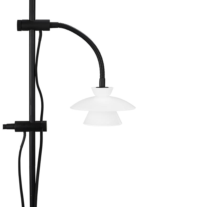 Lampe med hvid todelt skærm hænger fra en sort fleksibel slange, monteret på en lodret sort stang; sorte ledninger løber langs stangen mod venstre på hvid baggrund.