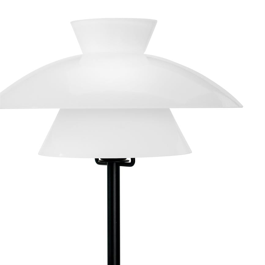 Lampe med tre hvide, lagdelte skærme står på en sort stang; den viser et minimalistisk design og er isoleret mod en neutral, hvid baggrund.