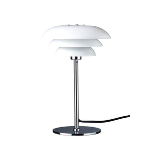 Bordlampe står på en rund kromfod, støttet af en slank kromstang; tre lagdelte hvide lampeskærme øverst; sort ledning fører ud til højre på hvid baggrund.