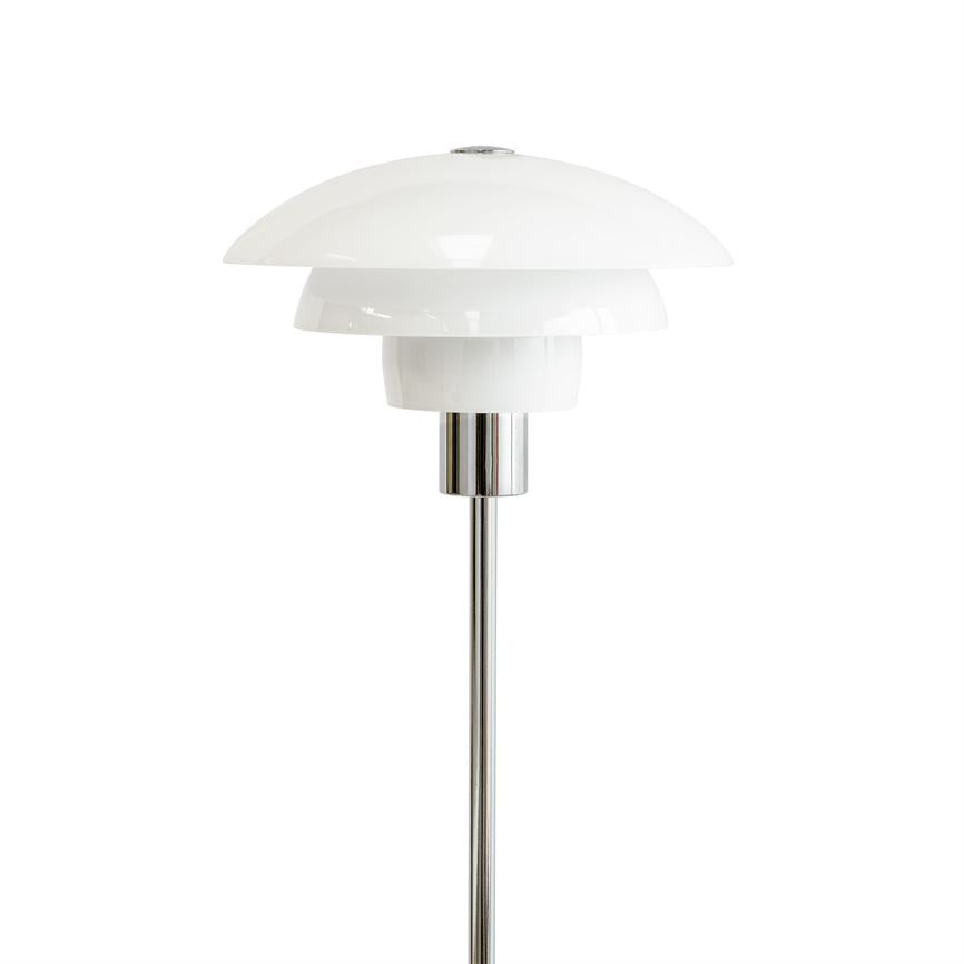En hvid, trelags rund lampskærm monteret på en slank kromstang; lampen står oprejst centralt mod en ensartet hvid baggrund.