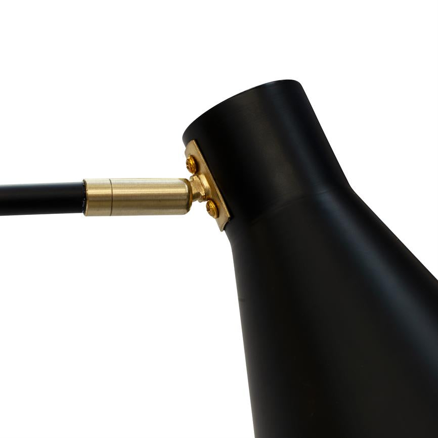 Sort lampehoved er forbundet med et messingbeslag og en sort arm, let vinklet mod højre, placeret på en neutral hvid baggrund.