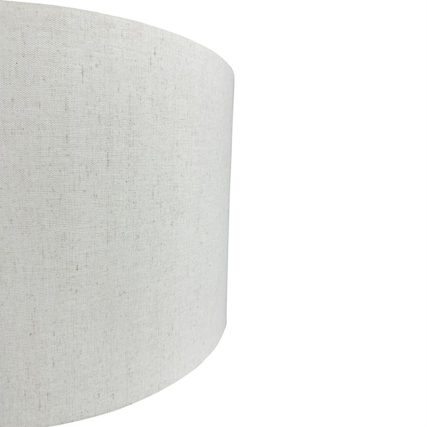 Cylindrisk lampeskærm i lyst, groftvævet stof; står i forgrunden, delvist beskåret og buer ind mod højre; neutral hvid baggrund.