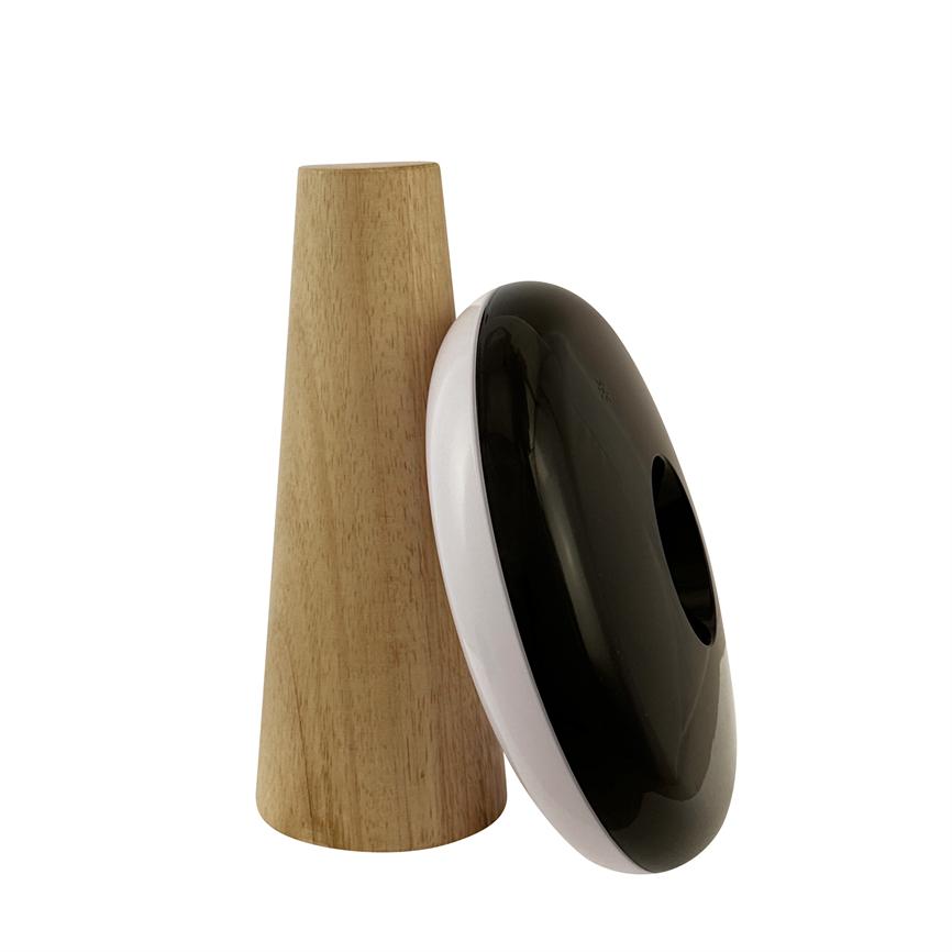 Sort-hvid, donutformet enhed med glansfuld sort front læner sig mod en opretstående, kegleformet træstøtte; begge står på ensartet hvid baggrund i et produktfoto.