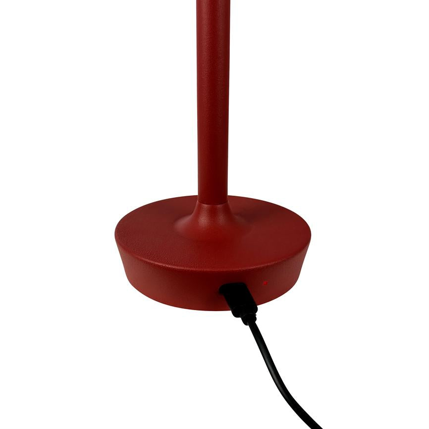 Rød lampesokkel med slank stok; et sort strømstik er tilsluttet i soklens side, hvor et lille rødt indikatorlys ses. Objektet står på en ensartet hvid baggrund.