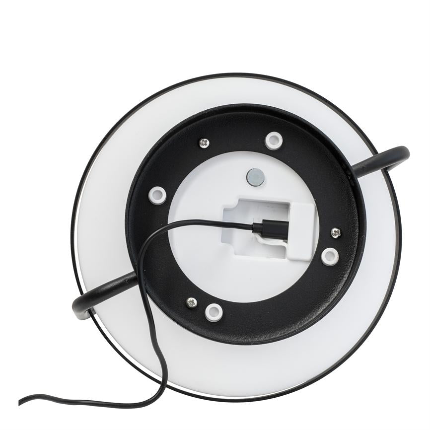 Rund lampe set bagfra, med sort metalring og hvid diffusor; et sort kabel er tilsluttet en hvid stikforbindelse, to sorte arme strækker sig ud mod en hvid baggrund.