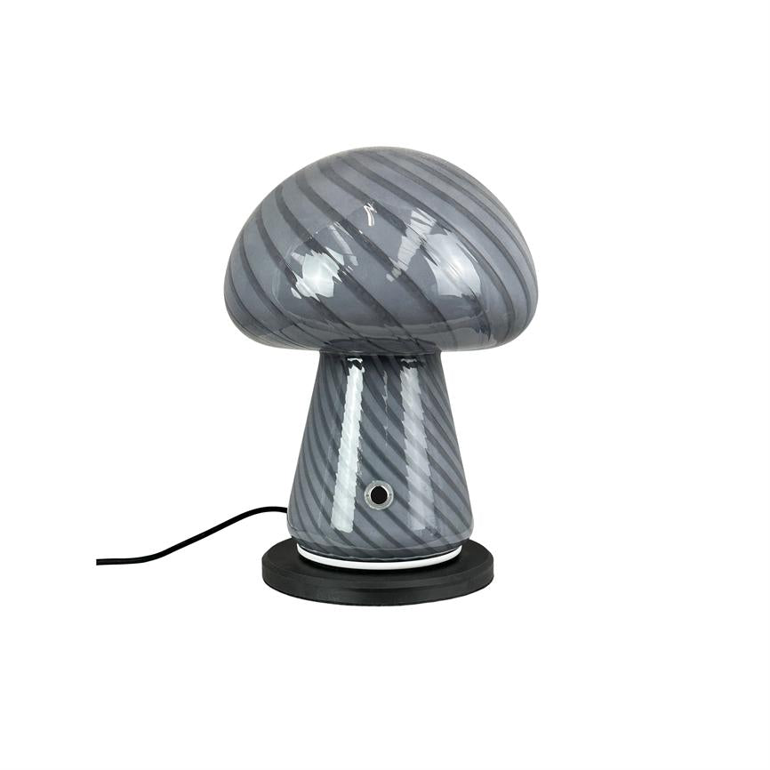 Svampeformet lampe af grå, diagonalstribet blankt glas står på en sort rund fod med et lille metaludtag på skaftet; et sort kabel løber mod venstre på hvid baggrund.