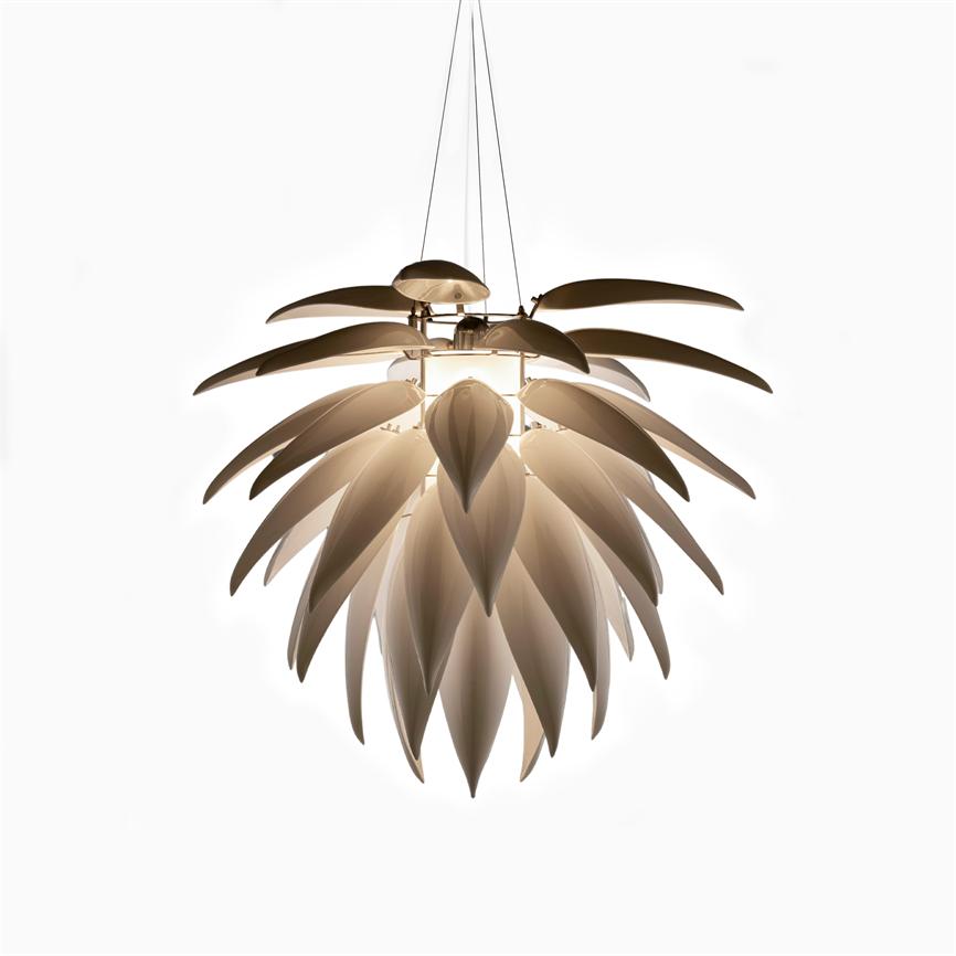 En hængende lysekrone-lampe formet som lagdelte blade udsender blødt, varmt lys, ophængt i tynde kabler mod en neutral, hvid baggrund.