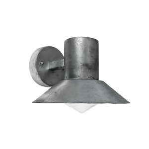 Metal væglampe hænger, kaster lys nedad; rå, mørkegrå cylinderformet armatur med bred, skrå skærm og hvid pyramideformet diffusor, monteret på rund vægplade i lignende metal.