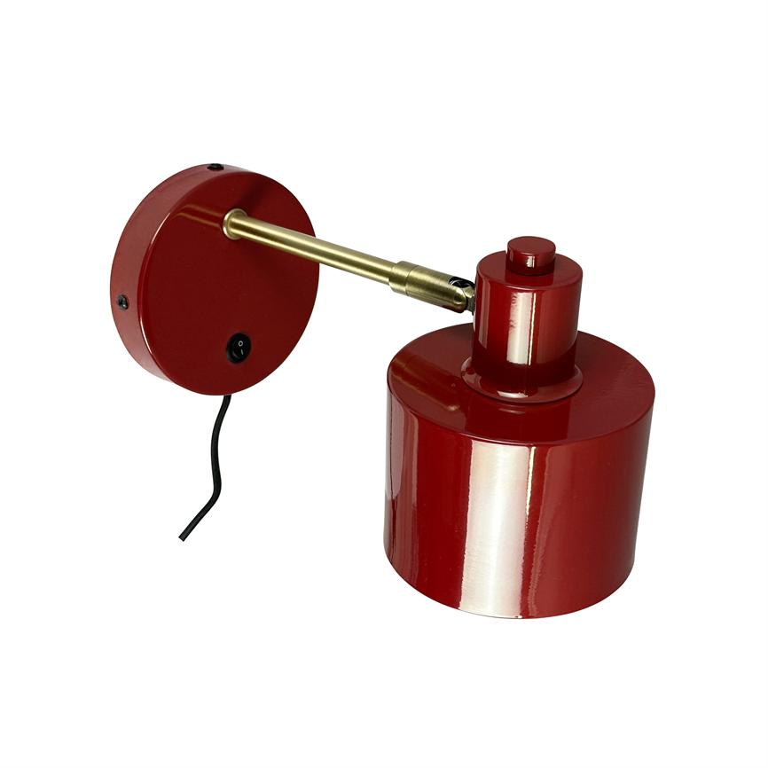 Rød metal væglampe med cylindrisk skærm, monteret på en justerbar messingarm, rund vægplade med afbryder og synlig sort ledning, placeret mod hvid baggrund.