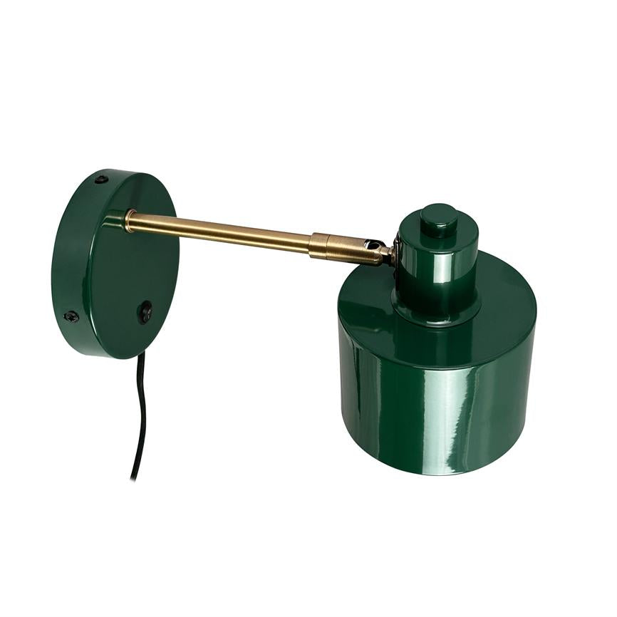 Væglampe med grøn, blank lampskærm monteret på rund grønt vægbeslag; en messingarm forbinder skærm og beslag, armens led gør lampen justerbar, sort ledning hænger ned, hvid baggrund.