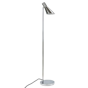 En høj krom gulvlampe står med en slank stang, rund bund og et vinklet, kegleformet lampehoved rettet nedad; sort ledning ligger løst ved foden på hvid baggrund.