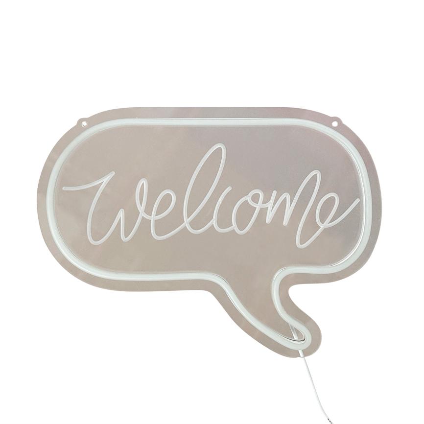 Et talebobleskilt lyser teksten 'welcome' i hvid neonlys; skiltet har en lys rosa baggrund med hvid kant, synlig hvid ledning og to ophængshuller.
