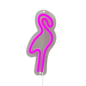En flamingoformet neonskilt lyser i pink konturlinje på en grå metallic plade, hænger mod en hvid baggrund med synligt kabel og ophængshuller.