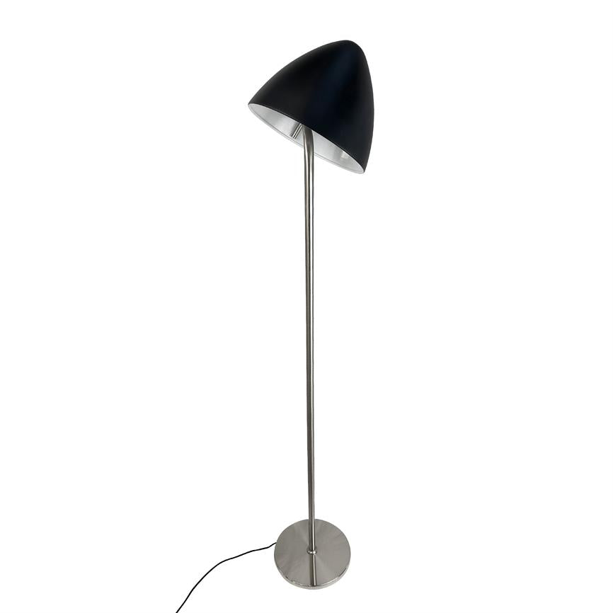 Gulvlampe med skråtstillet sort skærm står på en tynd sølvmetalstang med rund fod; en sort ledning ligger henover hvid baggrund.