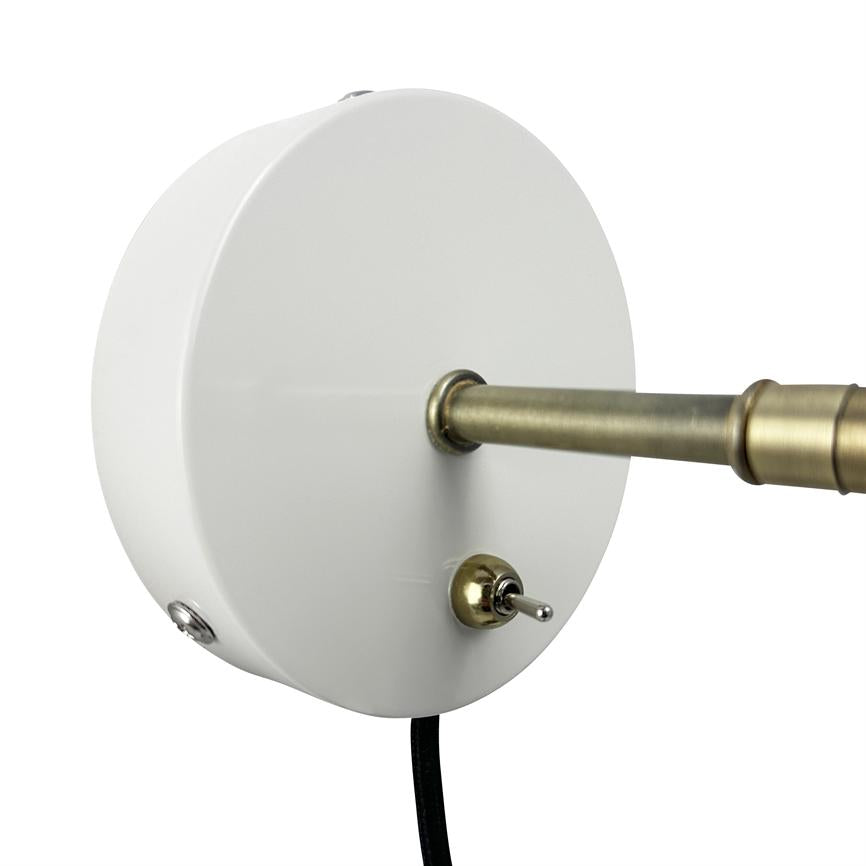 Rund hvid vægmonteret lampebase holder en udgående messingstang og en lille vippekontakt; sort ledning hænger ned, vist i nærbillede mod en neutral hvid baggrund.