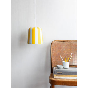 Gul-hvid stribet pendellampe hænger over en rottingstol med bogbunke, krus med blyanter og en lille skål, foran en hvid væg.
 
 Tekst: "Wonderwall Case Studies"; "BYGNINGSKULTUR OG BEVARINGSVÆRDIER"