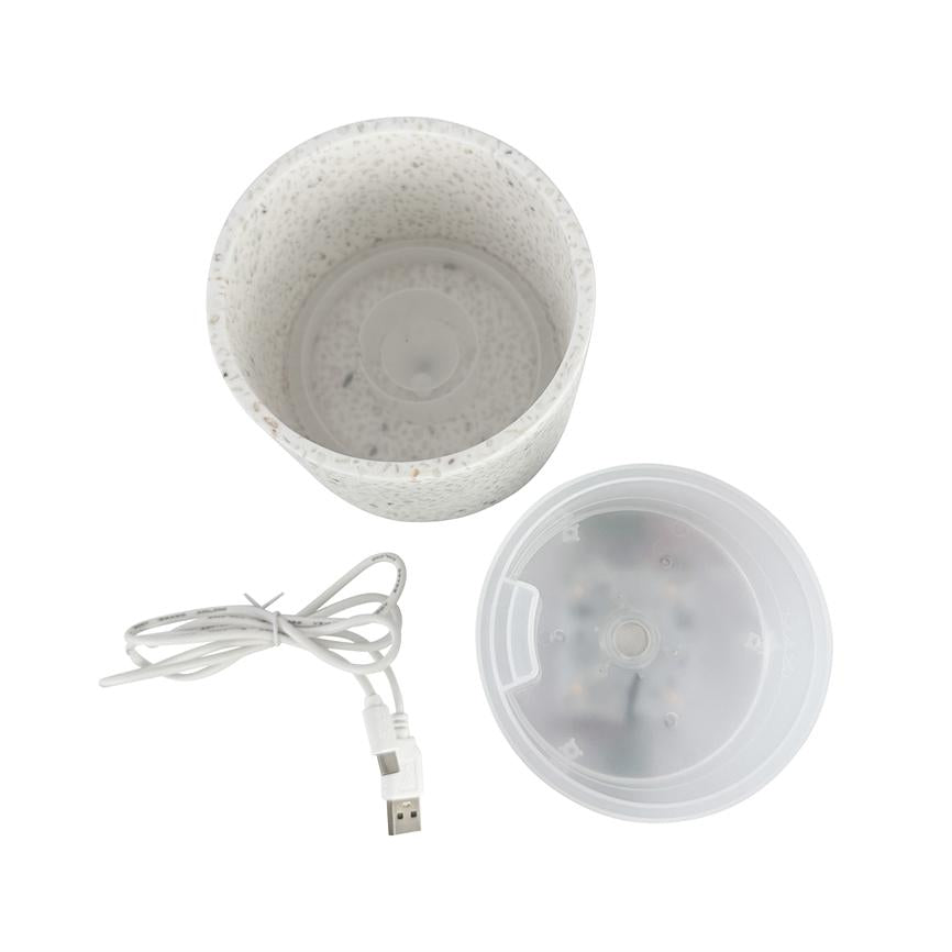 Hvid, spraglet cylindrisk beholder; den er adskilt i tre dele med et gennemsigtigt plastlåg og et sammenrullet USB-kabel; delene ligger på en hvid baggrund.