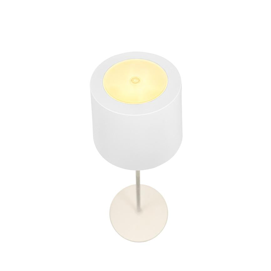 Bordlampe udsender varmt, svagt gult lys; hvid cylindrisk skærm, tynd metalstang og rund base, fotograferet ovenfra mod en hvid baggrund.