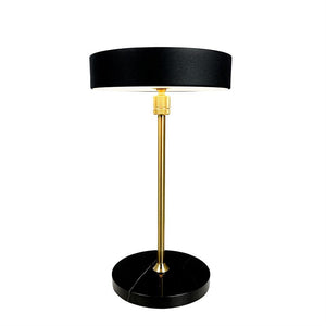 Bordlampe med sort cylindrisk skærm, slank guldfarvet stang og rund sort marmorfod; står oprejst på hvid baggrund, funktionel og elegant.