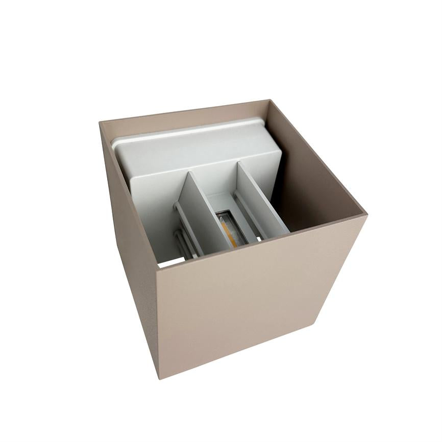 Kvadratisk beige væglampe rummer et hvidt indvendigt LED-modul med tre vertikale skillevægge; lampen ses skråt oppefra mod en ensartet hvid baggrund.