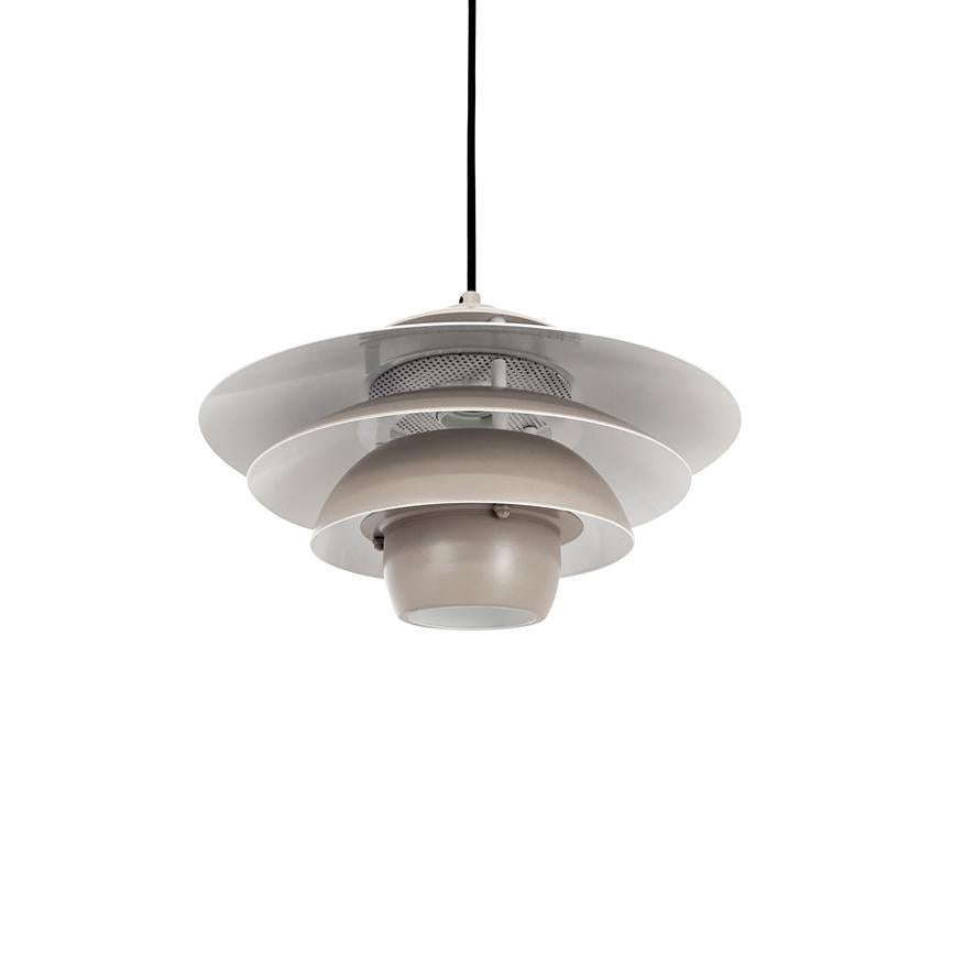En lagdelt, rund hængelampe hænger i en sort ledning over en neutral hvid baggrund; flere brede metalskærme omkranser en central beige kuppel med nedadvendt diffuser.