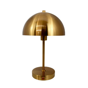 Bordlampe i børstet messing med halvkugleformet skærm, monteret på en slank stang og rund fod; står stille mod en neutral hvid baggrund.